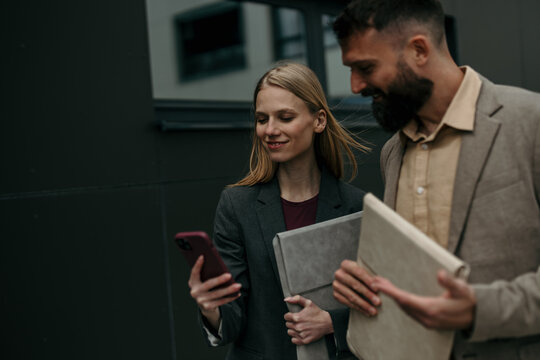 Business professionals walking and using smartphone outside office