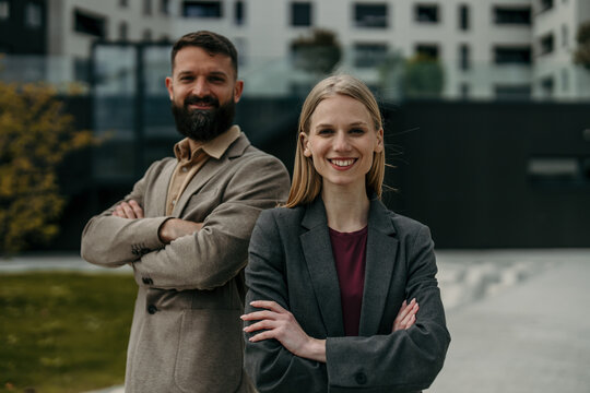 Business partners standing outdoors with crossed arms smiling