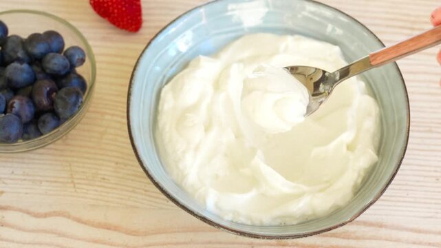 Greek yogurt scooping with spoon. Texture of thick homemade greek yogurt for healthy breakfast. Dairy product. Delicious organic creamy yogurt or sour cream scoop close up.