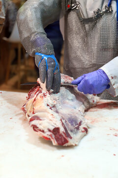 experto carnicero cortando carne de ternera en la carnicer&iacute;a con guantes de malla