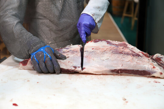 matarife cortando carne de vacuno con guantes de malla