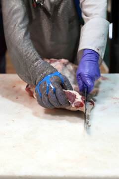 carnicero matarife cortando carne de ternera con guantes de malla especial de especiar carne