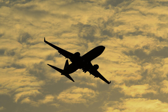 The silhouette of a four-engine airliner against a sunset sky.