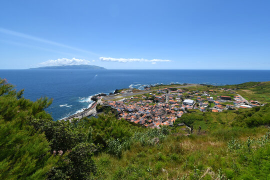 Coastal village of Vila do Corvo with airport and harbor overlooking the ocean and distant island of Flores, Azores archipelago