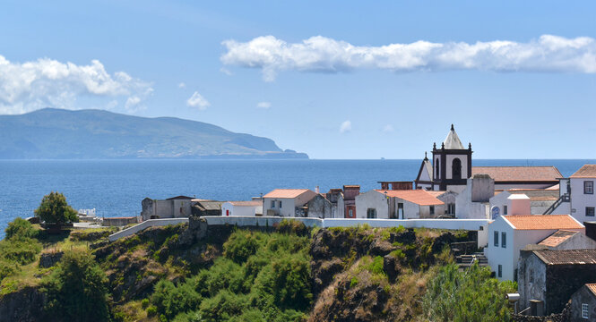 Coastal village of Vila do Corvo with airport and harbor overlooking the ocean and distant island of Flores, Azores archipelago
