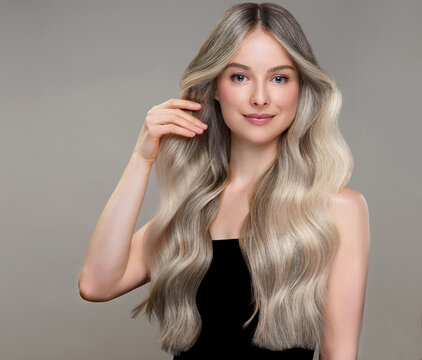 Airtouch coloring technique. Blonde hairstyle: long wavy curls. Beauty  girl with long  and   shiny wavy  Hair , toning, shatush and balayash .  Beautiful   woman model with curly hairstyle . Cosmetol