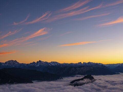 Red-colored plume clouds over the Berchtesgaden Alps at dusk, fog in the valley, Hochstaufen, Chiemgau Alps, Upper Bavaria, Germany