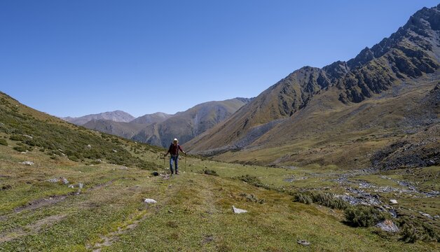 Mountaineers on a hiking trail, green high valley with mountains, Keldike Valley on the way to the Ala Kul Pass, Tien Shan Mountains, Kyrgyzstan