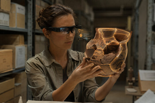 Female Archeologist Using Augmented Reality Smart Glasses to Analyze and Reconstruct Ancient Pottery in Museum Archive Laboratory