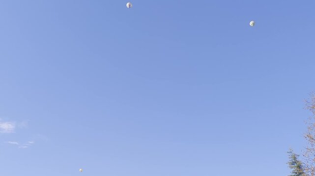 Sky above City Park in Vic Spain. Two bright balloons float gently in blue sky. A serene moment captured. Perfect for family and outdoor themes. Bright colors attract attention.