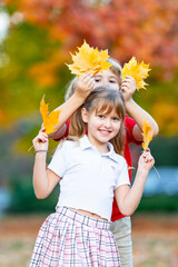 Obraz premium Friends kids enjoy autumn leaves. Friends children smile in autumn park. Friends kids hold colorful autumn foliage. Friends children share happy autumn fun.