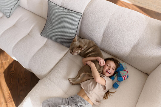 Child hugging dog on cozy sofa