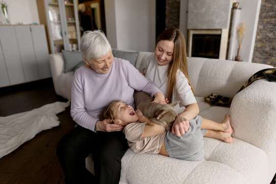 Three generations playing with dog at home