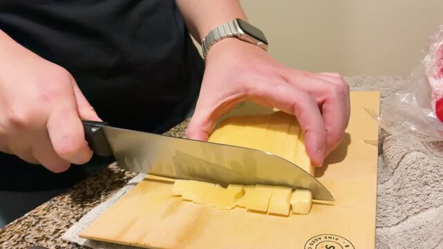 Female chef hands cutting cheese cubes on a wooden board preparing an appetizer platter, traditional Picada Argentina