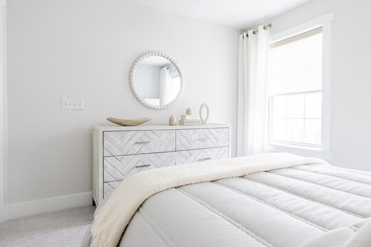 Serene White Bedroom with Chevron Dresser, Round Mirror and Fluffy White Bedding

