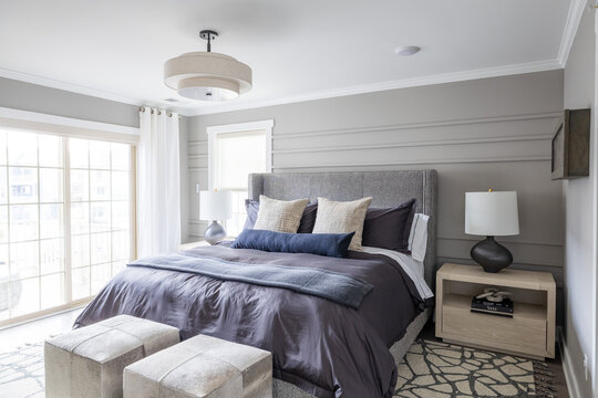 Modern Gray Bedroom with Dark Bedding, Upholstered Ottomans and Patterned Rug