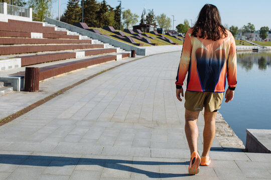 Anonymous stylish man with long hair walk near the river