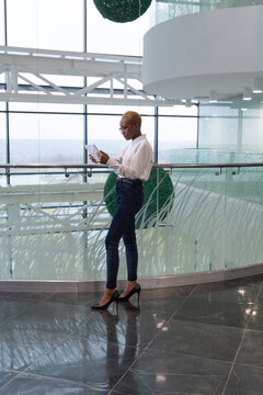 Black businesswoman using tablet in office hallway