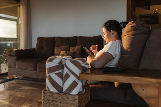 Individual relaxing at living room scrolling cellphone