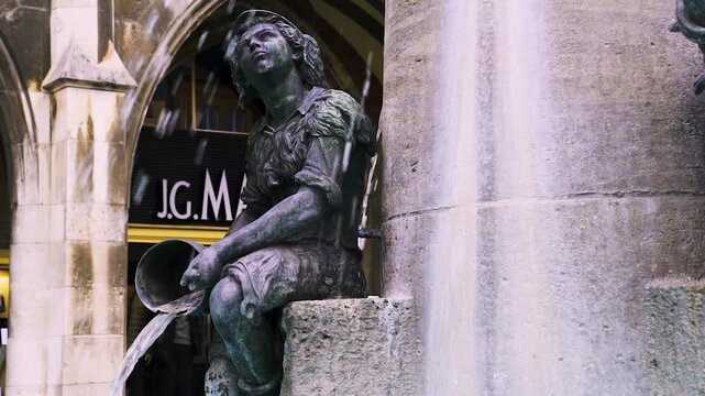 Detailaufnahme einer Brunnenfigur mit Eimer am Fischbrunnen in M&uuml;nchen