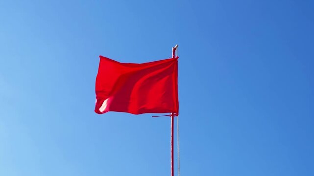 red flag flutters in wind against sky
