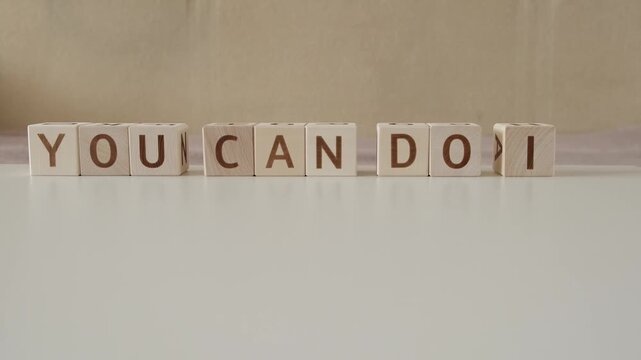 motivational phrase you can do it, laying out  by hand from letters on wooden cubes, slow motion
