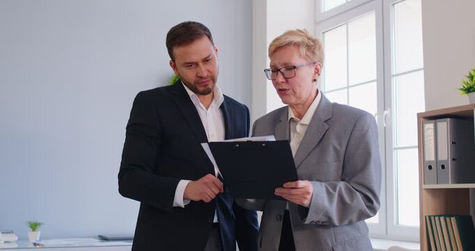 Diverse business people in office, mature woman and man, positive consultant and client, meeting for consultation, getting agreement, enjoying professional communication, working on collaborative task