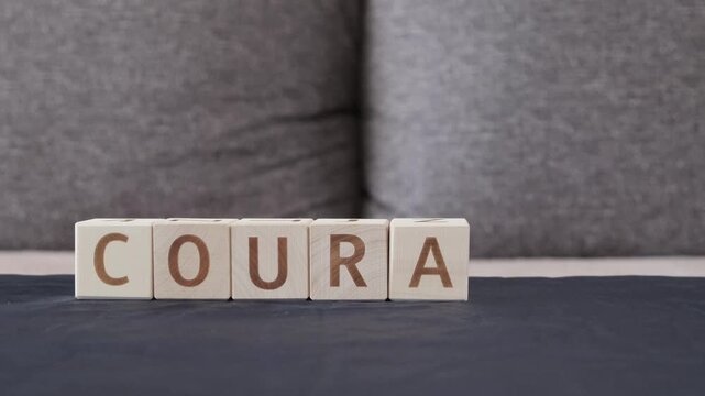 motivational word courage, laying out  by hand from letters on wooden cubes, slow motion
