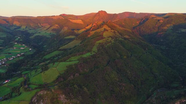 Aerial view of the lush green hills and volcanic terrain surrounding Miradouro dos Caimbros at sunset in Cedros, Acores, Portugal.