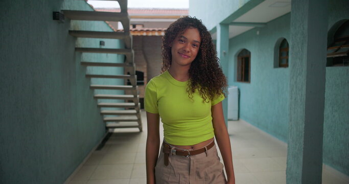 Teenage girl of African descent smiling confidently while standing outdoors, casual setting with bright expression, showcasing individuality and youth