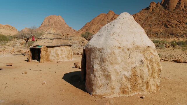 Traditional african huts in himba village near spitzkoppe mountain range in the namibian desert on a sunny day