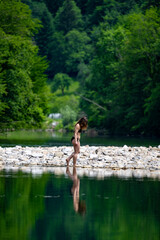 Fototapeta premium Woman enjoying a tranquil moment beside emerald waters of the Kupa River, highlighting sustainable holidays, mindfulness and authentic rural experiences