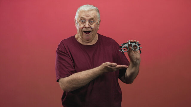 Man holding a trial frame phoropter while touching temple with hand during eye examination in studio; frustration vision test.