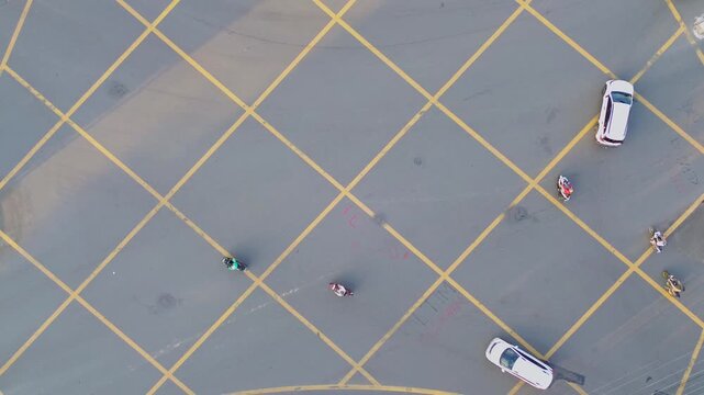 Aerial view of the yellow box junction markings on Jalan Letnan Jendral Suprapto with a car and a pedestrian in Kecamatan Samarinda Ulu, Kalimantan Timur, Indonesia.