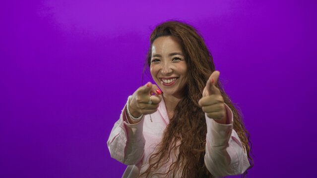 Woman points finger at camera with hands visible in studio against purple backdrop; confidence connection.