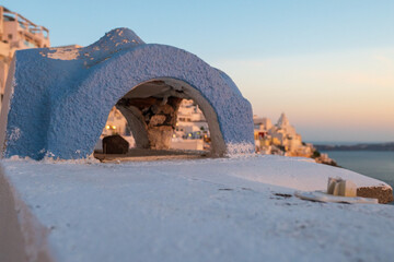Bluewashed arch framing caldera buildings and sea at golden hour on Santorini, Greece. © Andrei Tomas