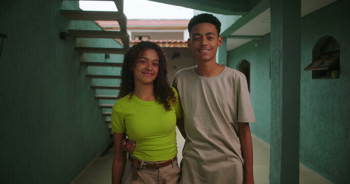 Brother and sister of African descent standing arm in arm in a corridor smiling warmly showcasing sibling love and connection