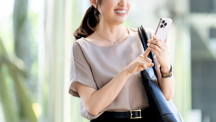 屋外でスマートフォンを使う女性・ビジネスウーマン, Businesswoman Using a Smartphone Outdoors © Trickster*