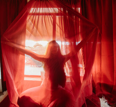 Woman opening red curtains 