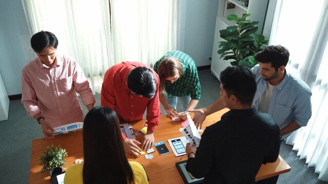 Top view of skilled Ui designer brainstorming by writing on sticky notes and planning about Ux Uo design or mobile phone interface wireframe design with diverse develop team at boardroom. Convocation.