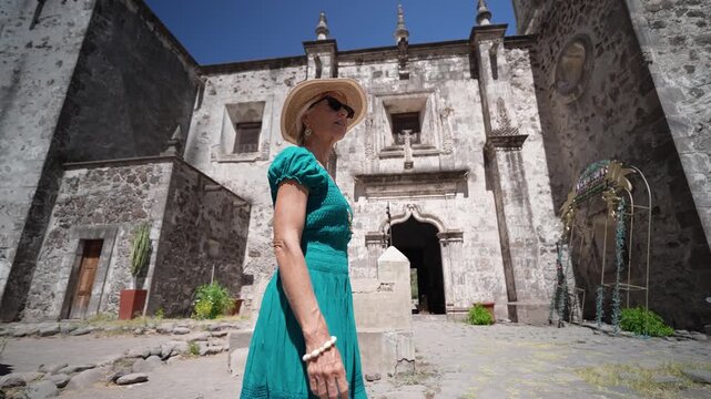Senior woman enjoys walking around San Javier Mission in Loreto, Baja California Sur as the sun rises over the desert landscape