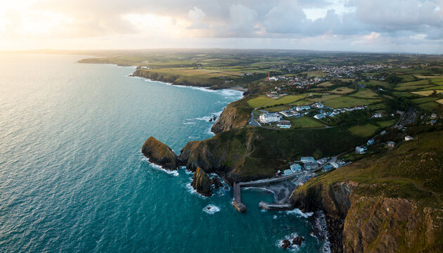 Aerial view from the sea of the Cornish fishing village of Mullion Cove and its historic harbour on the Lizard Peninsula in Cornwall, UK