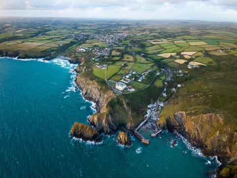 Aerial view from the sea of the Cornish fishing village of Mullion Cove and the Lizard Peninsula in Cornwall, UK