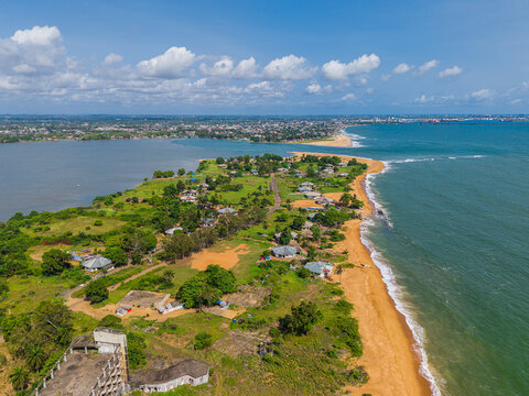 Aerial view of the coastline featuring sandy beaches, lush green vegetation, and scattered residential houses along the oceanfront in Monrovia, Montserrado, Liberia.