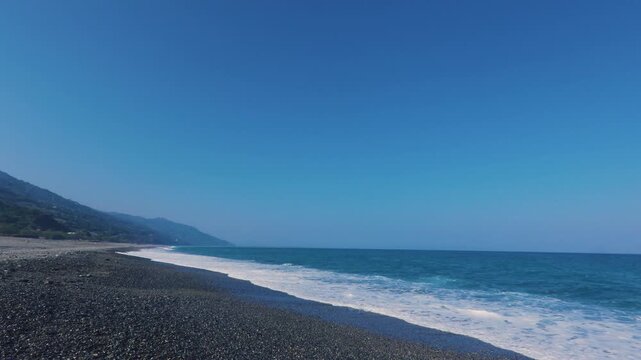 Scenic view of white waves on the beach at Taimali Millennium Dawn Memorial Park under a clear blue sky