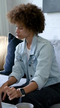 Vertical video: Joining call, woman in denim jacket typing, speaking, laughing on sofa with laptop