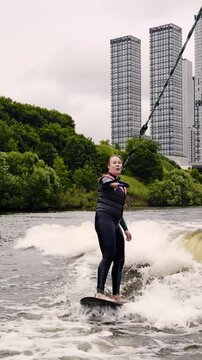 Person wakeboarding on a lake near tall buildings during cloudy weather in the afternoon