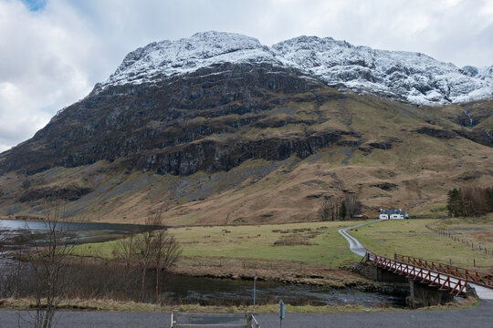 A little bridge over the River Coe and Achnambeithach cottage in front of Coire nam Beitheach, Aonach Dubh and slopes of Stob Coire nan Lochan a peak of Bidean nam Bian in Glencoe, Scottish Highlands.
