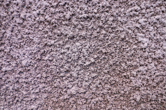 Texture of coarse wall plaster with a pronounced relief and rough surface. Decorative coating is made in a muted pink-brown or lilac shade. Ideal modern background for design, architectural projects, 