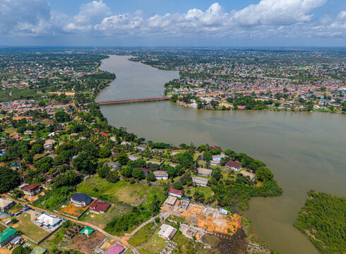 Aerial view of the Mesurado River and the bridge connecting urban districts, with residential houses, lush vegetation, and coastal landscape in Monrovia, Montserrado, Liberia.